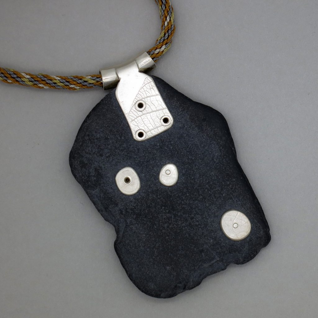Slate pendant with silver pebbles to anchor the rivets